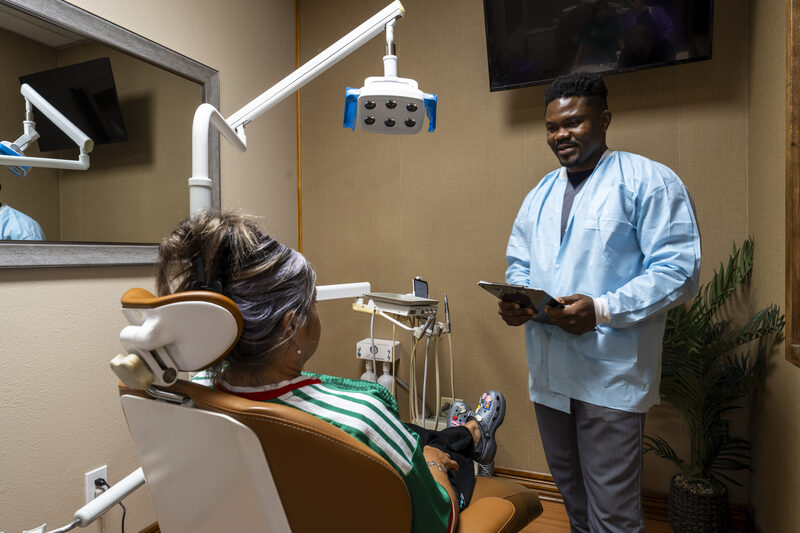 Dr. Patrick Kamgang smiling with a patient in a treatment room at Marshall H. Brown, DDS in Fort Worth, Texas